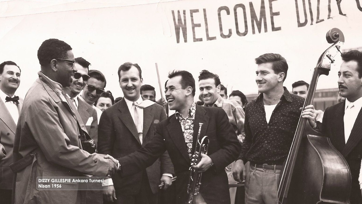 22 Nisan 1956, Ankara. Dizzy Gillespie’yle el sıkışan Muvaffak Falay, yanında Erol Pekcan var, kontrbasıyla Süheyl Denizci ve tromboncu Sabahattin Doğanöz. Kaynak: Türk Amerikan Derneği.